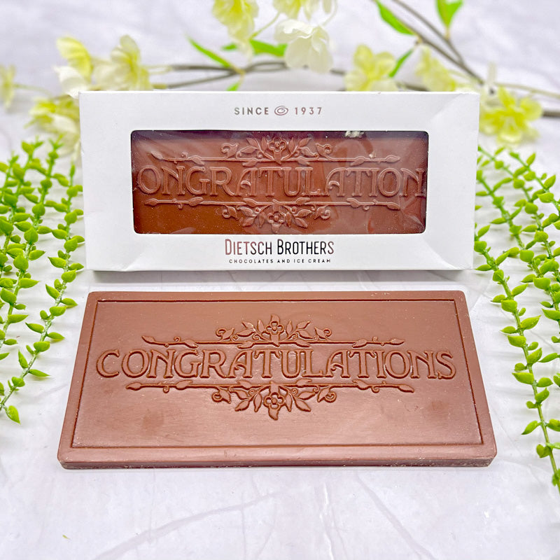 Milk chocolate bar that features "CONGRATULATIONS" across it, and floral borders along the top of the text as well as below it.