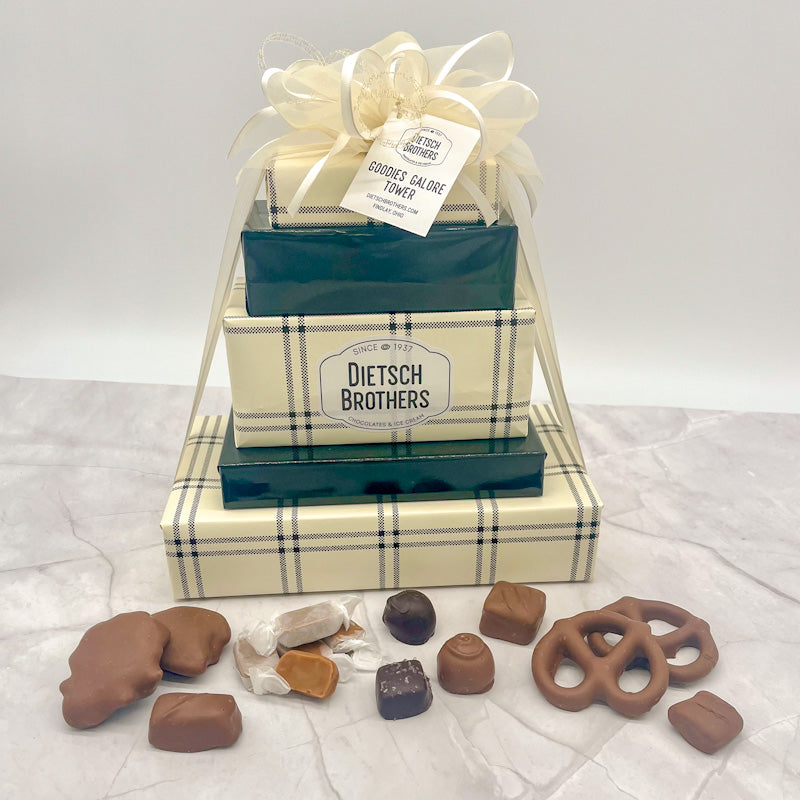 Five layered tower of assorted treats wrapped in cream and black plaid and green wrapping papers and tied with a cream colored bow.