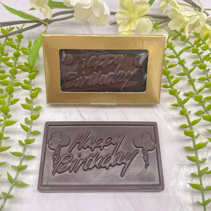 Dark chocolate bar that features a raised text "Happy Birthday" across it, with balloons on both the left and right side of the text