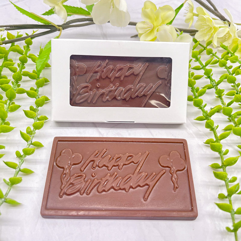 Milk chocolate bar that features a raised text "Happy Birthday" across it, with balloons on both the left and right side of the text