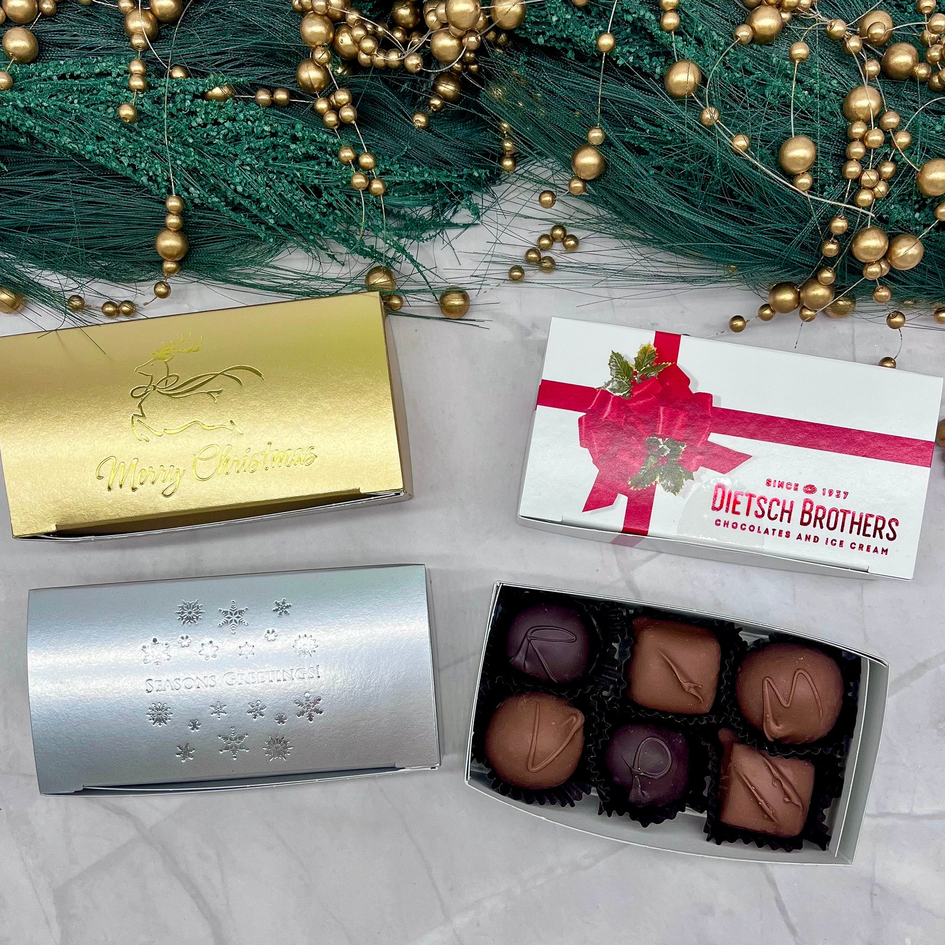 Assorted chocolates in open box with decorative packaging on a festive background