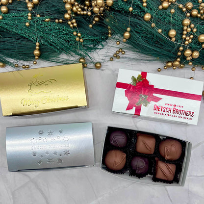 Assorted chocolates in open box with decorative packaging on a festive background