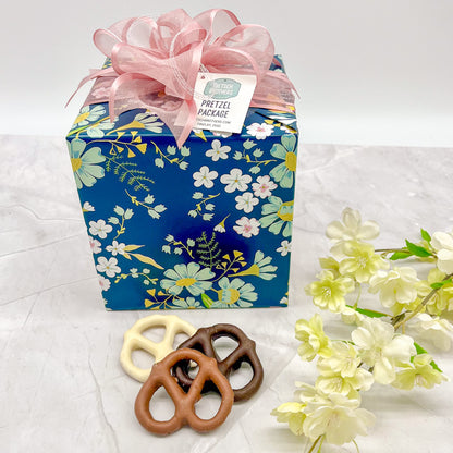 Pretzel package wrapped in blue floral paper and topped with a pink bow