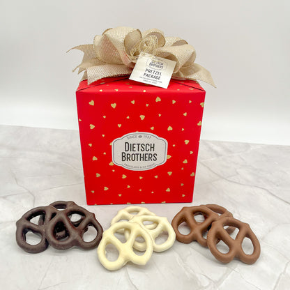 Pretzel package wrapped in red paper featuring gold hearts and a gold bow