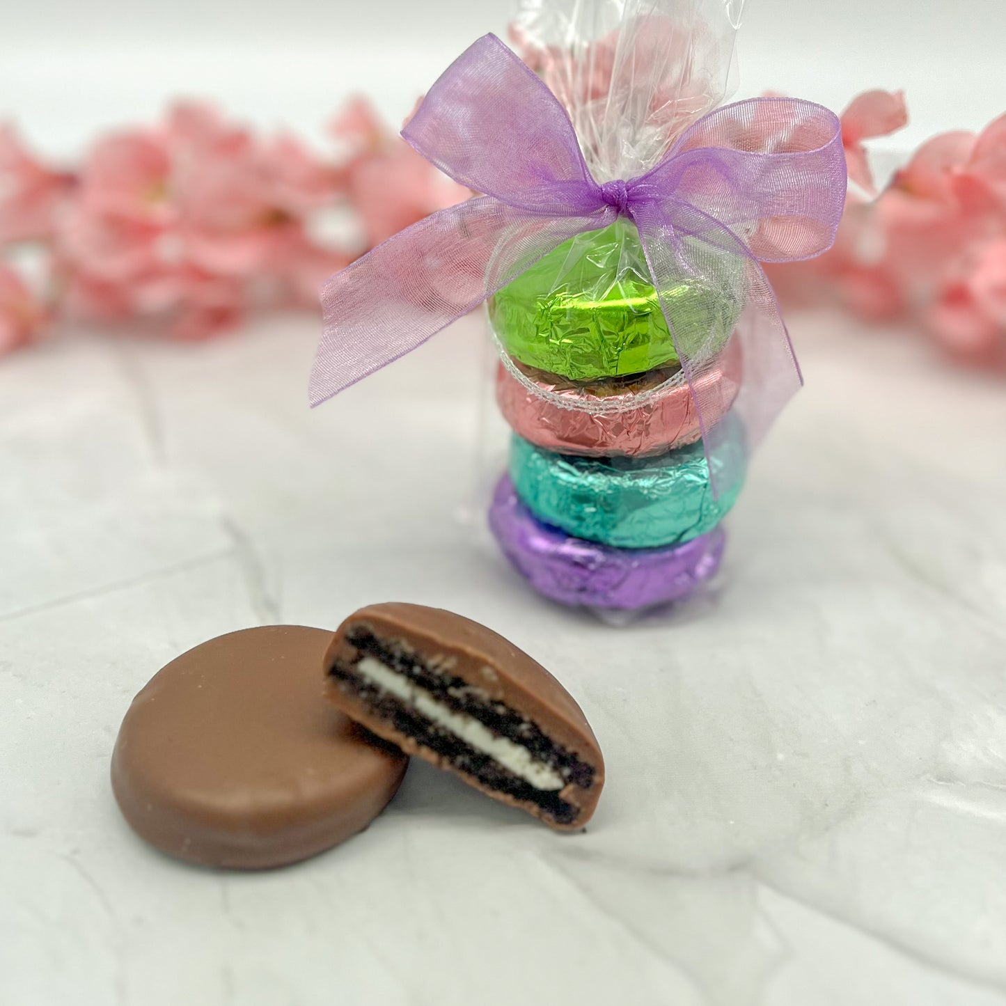 Four-piece pastel foil wrapped milk chocolate oreos in clear bag and tied with a colored purple bow