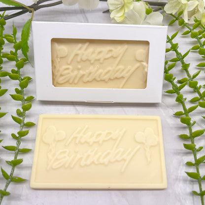 White chocolate bar that features a raised text "Happy Birthday" across it, with balloons on both the left and right side of the text