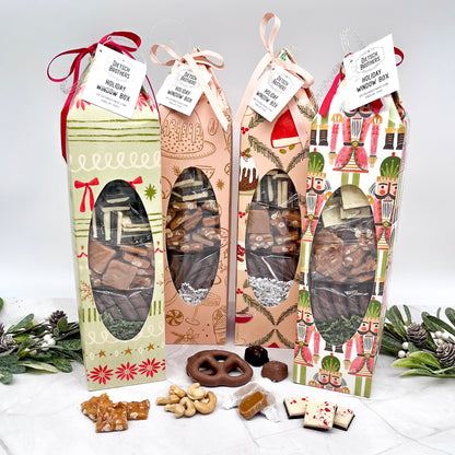 Four holiday-themed gift boxes with visible chocolates and nuts on a white surface.